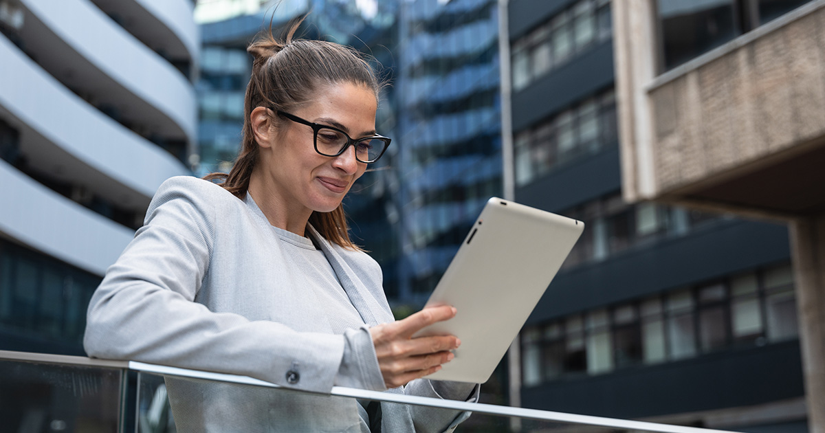 Portrait of a successful businesswoman using a digital tablet in front of a modern office building.