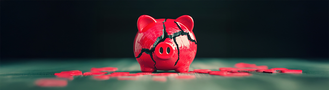 Auf dem Bild ist ein rotes Sparschwein mit großen Rissen zu sehen.