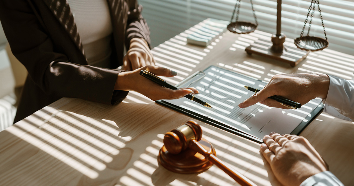Lawyer is pointing with a pen where to sign a legal document during a meeting in the office.